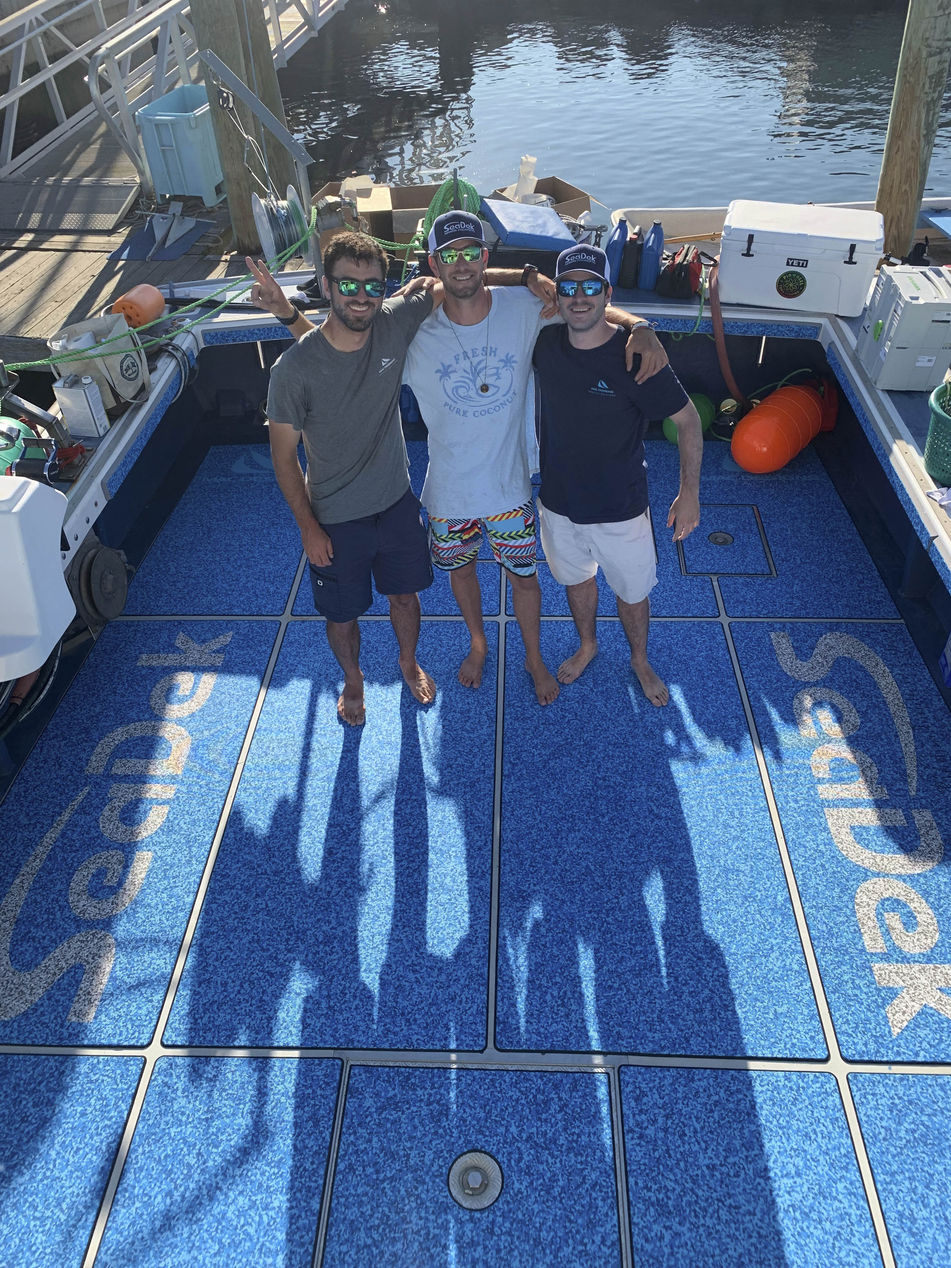 The SeaDek covered deck of the Pinwheel with 3 men standing on it.