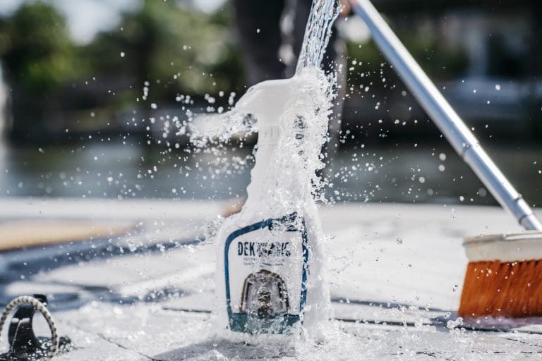 Water being poured onto a bottle of Dek Magic Cleaner.